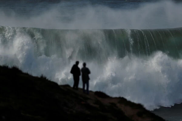 People gather to watch a tow-in surfing session at Praia do Norte in Nazare