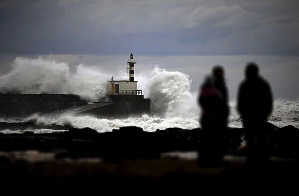 People look at huge waves crashing on the San Esteban de Pravia seafront