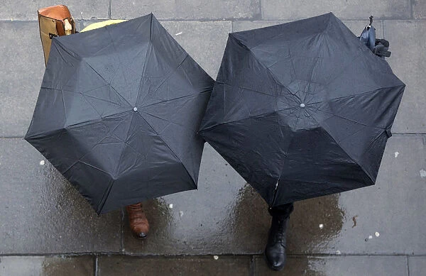 People shelter under umbrellas as they walk through central London