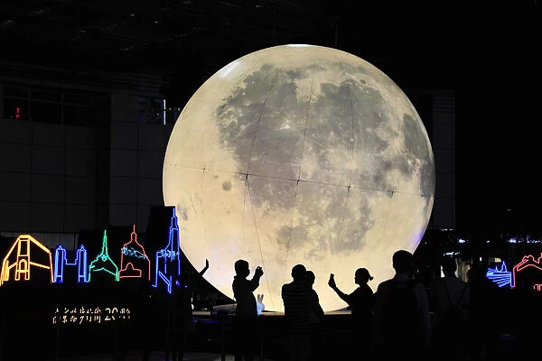 People stand in front of a moon installation at Nanjing Road on the eve of the Mid-Autumn