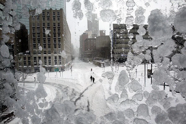 People walk through snow covered streets in Copley Square during a blizzard in Boston