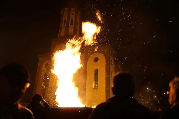 People watch burning Yule logs in front of the Church of the Holy Mother of God during