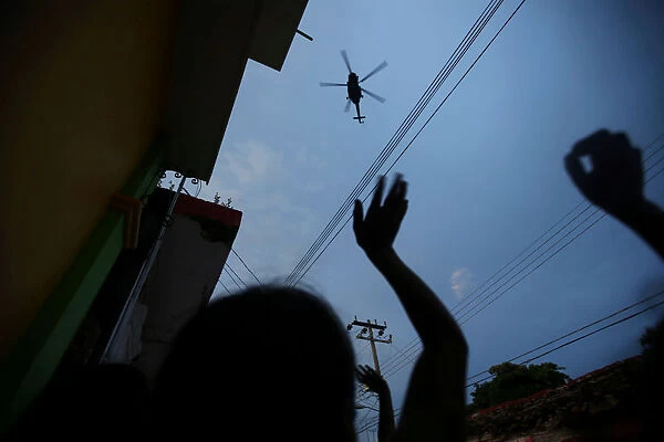 People wave at a helicopter after an earthquake that struck off the southern coast of