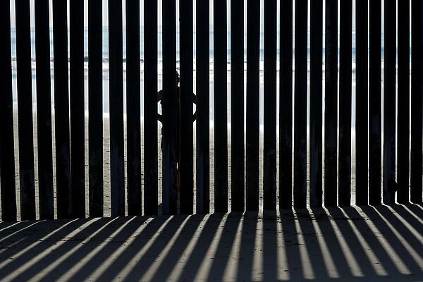 A person looks through the border wall towards the United States at Border Field State