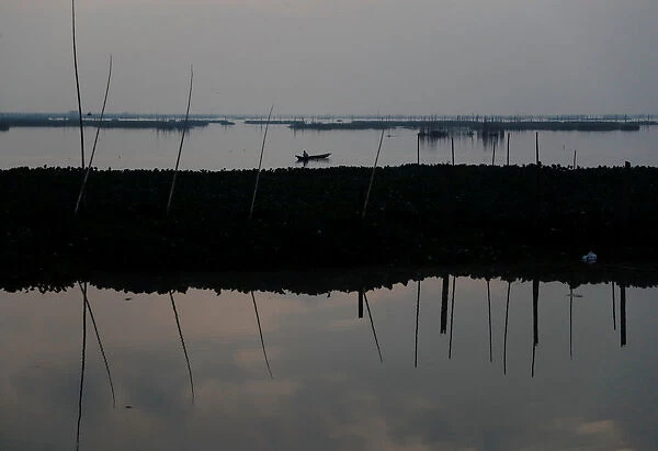A resident uses a net to fish at Laguna de Bay in Muntinlupa, Metro Manila