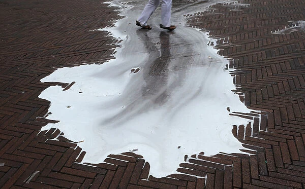 A reveller walks across a puddle of cleaning water on the fifth day of the San Fermin