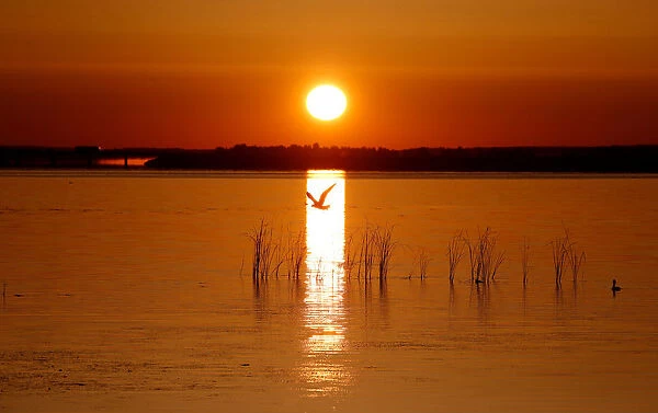 The rising sun illuminates the lake near the town of Vileika