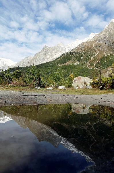 A segment of the Planpincieux glacier is reflected in water on the Italian side of the