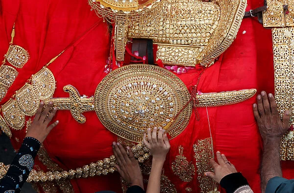 Shiite Muslims reach out to touch the gold-ornamentation of sword and shield