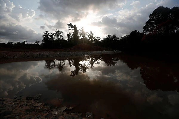 A small lake reflecting palm trees is pictured in Nsuaem district