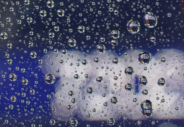 Stock prices displayed on an electronic board are reflected on raindrops on the window of