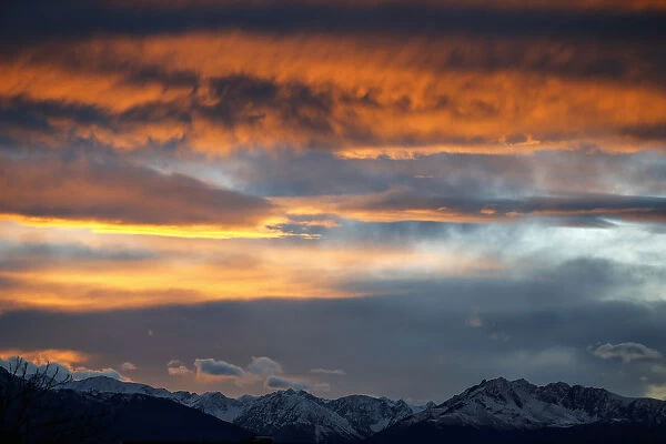 The summits of snow covered mountains are silhouetted during sunset in Innsbruck