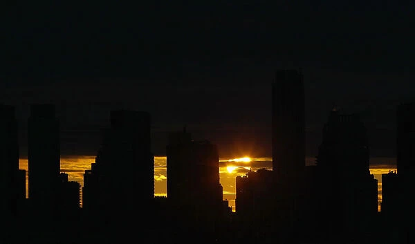 The sun rises behind the skyline of Manhattan as it is partially eclipsed by the moon
