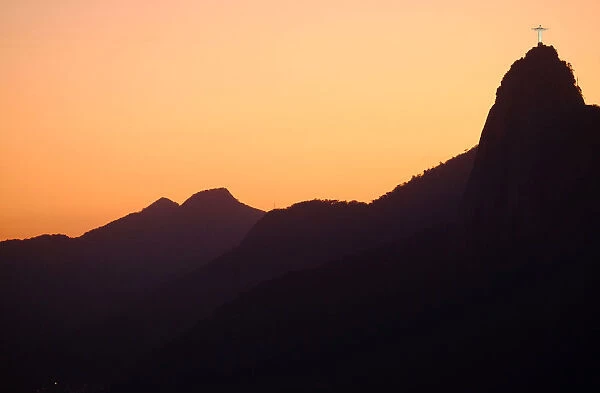The sun sets behind Christ the Redeemer statue on Corcovado mountain in Rio de Janeiro