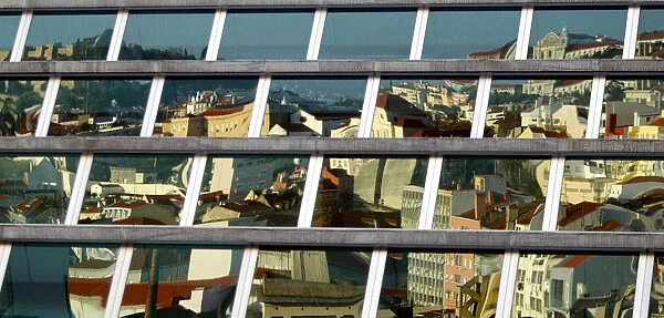 DOWN TOWN LISBON IS REFLECTED ON THE WINDOWS OF A MODERN BUILDING