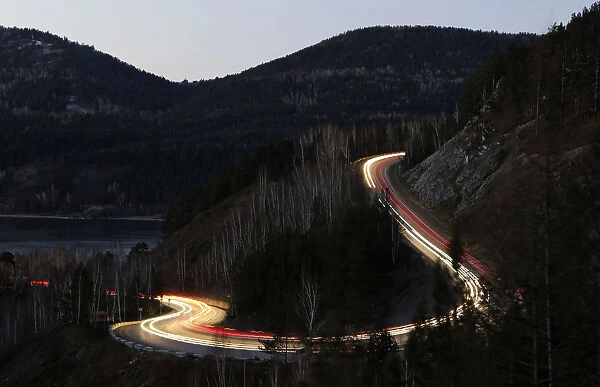 Vehicles drive along the M54 federal highway through Siberian Taiga district near
