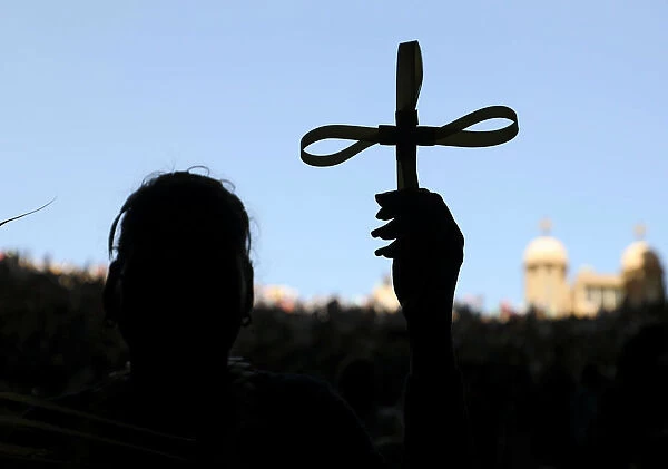 A woman holds a cross during a Coptic Orthodox Palm Sunday mass at the Samaan el-Kharaz