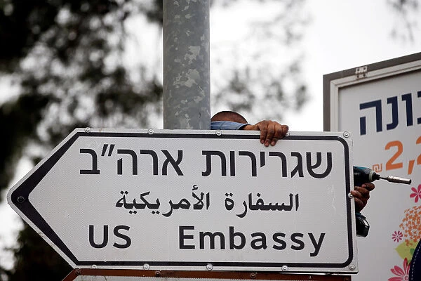 A worker hangs a road sign directing to the U. S. embassy, in the area of the U. S