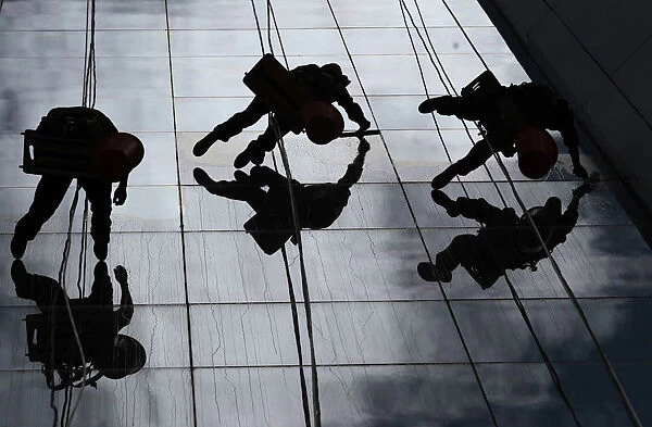 Workers clean the windows of a building in Quito