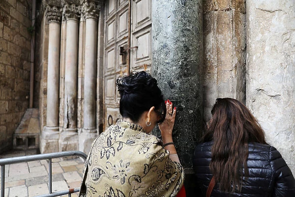 Worshippers pray next to the closed doors of the Church of the Holy Sepulchre in