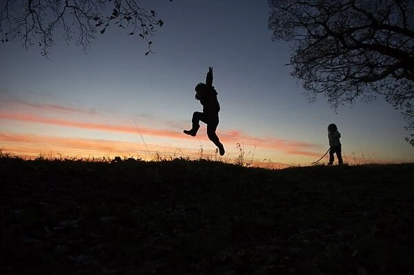 Young boy and girl playing at dusk on edge of woodland Norfolk winter