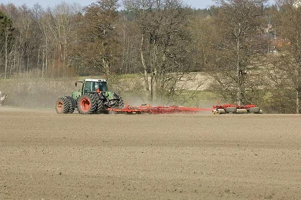 Fendt tractor pulling harrows and rollers, harrowing and rolling field, Sweden, spring