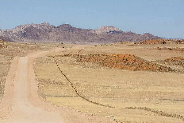 Africa, Namibia, Namib Desert. Long road and fence in desert
