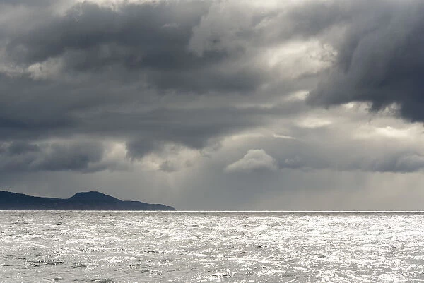 Australia, Tasmania, Tasman Sea. Dramatic line of sun on horizon through storm clouds