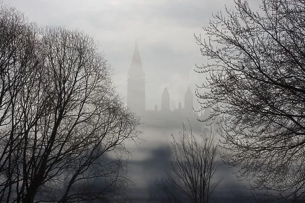 Canada, Ontario, Ottawa. Parliament Buildings seen between trees and ice fog on Ottawa River