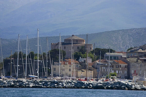 Corsica. France. Europe. Mast of boats & breakwater below citadel & other buildings of St