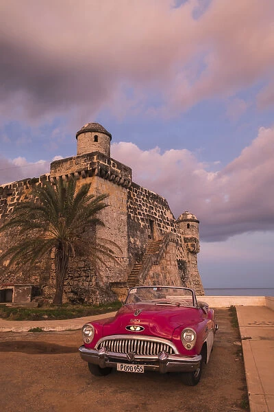 Cuba, Cojimar. Classic American car parked in front of a fort