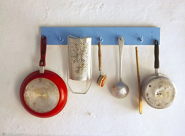 Greece, Corfu. Kitchen utensils hang on rack