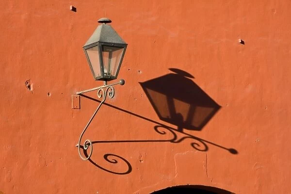 Guatemala, Antigua. A lantern with shadow on a colorful wall in the town of Antigua