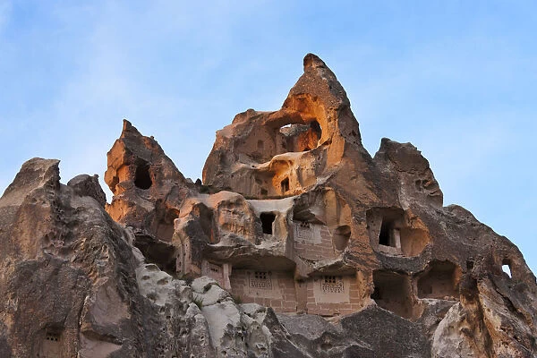 Houses carved into rock formation in Goreme at sunset, Cappadocia, Turkey