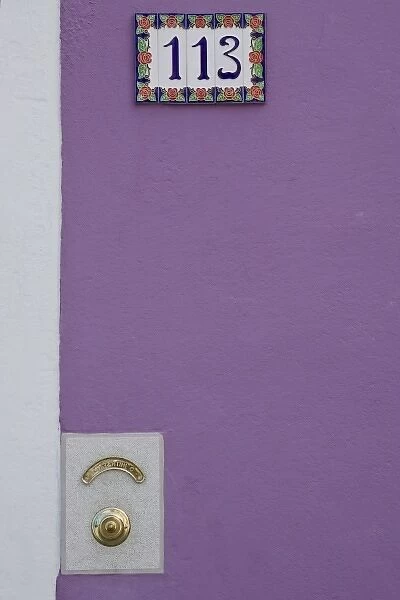 Italy, Burano. Purple stucco wall with white tile house number and brass doorbell button