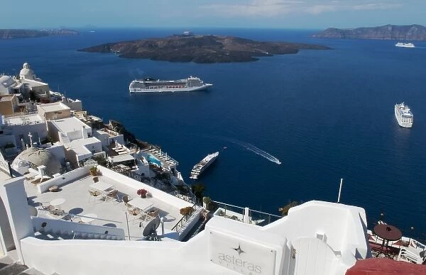 Looking down at white houses and the sea with ships at harbor in Santorini Greece