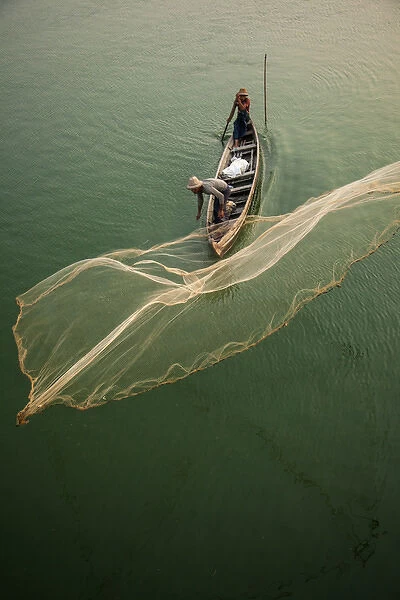 Myanmar, Mandalay, Amarapura. Fisherman casting net on Irrawaddy River. Credit as