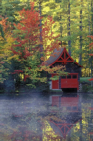 USA, New York, Adirondack Mountains. Boathouse and autumn reflections in lake. Credit as