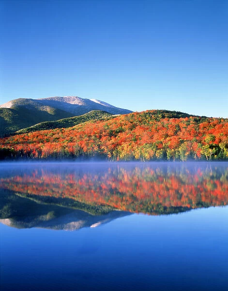 USA; New York; Snow Capped Algonquin Peak and autumn colors relecting in Heart Lake
