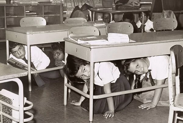 AIR RAID DRILL, 1962. Children under their desks during an air raid drill at P