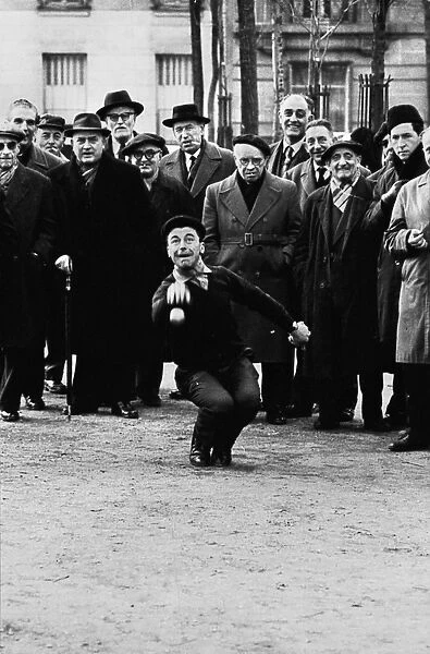 BOCCE PLAYER, c1945. A man throwing bocce balls while a crowd watches, probably
