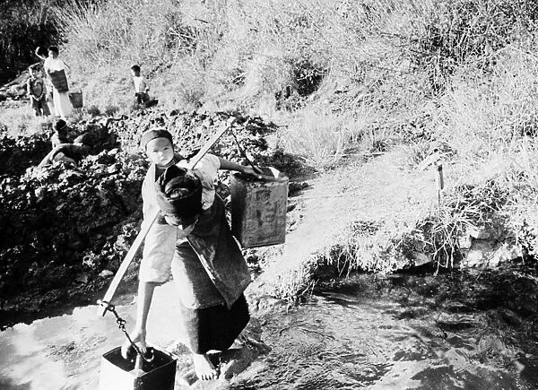 CHINA: SPRING WATER, c1940. A mother collects buckets of drinking water at a spring