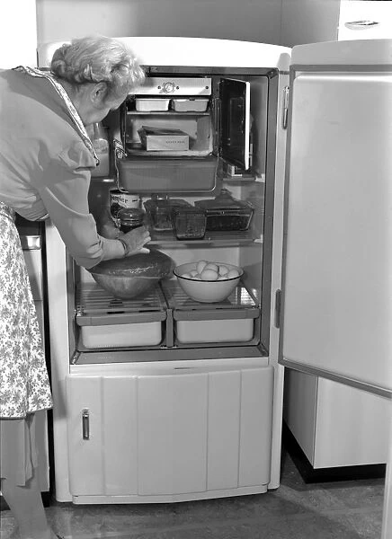 HOUSEWIFE, 1942. An American woman removing an item from her icebox. Photograph by Ann Rosener
