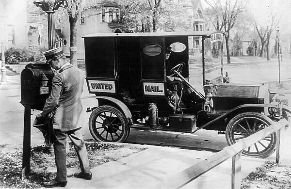 MAIL CARRIER, c1915. An American mail carrier emptying a mailbox, with his mail truck at the curb