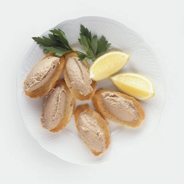 Anchoiade, a puree made from tuna, served on slices of bread with lemons and herb garnish, a typical dish from Provence, France, view from above