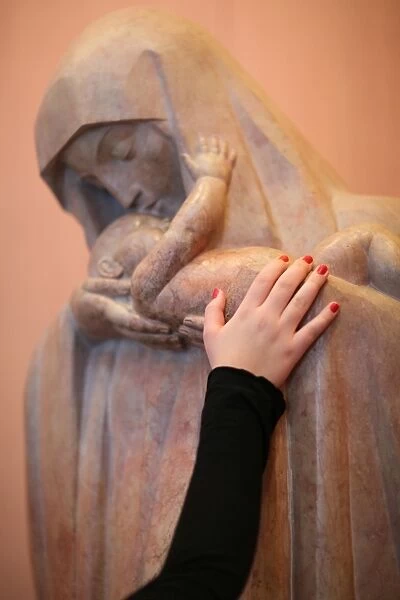 Believers hand on a Virgin and child statue