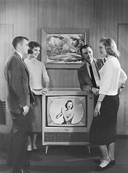 Two couples standing next to television