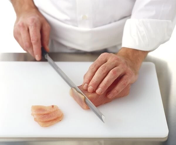 Cutting thin slices from a block of raw yellowtail tuna (hamachi)