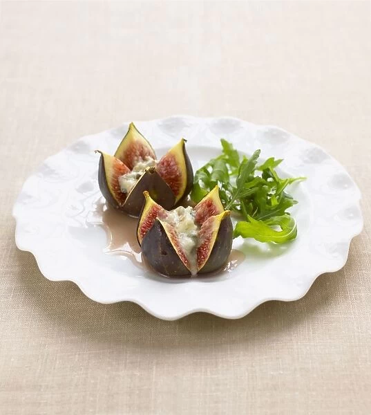 Figs served with melted gorgonzola cheese and green salad on white plate