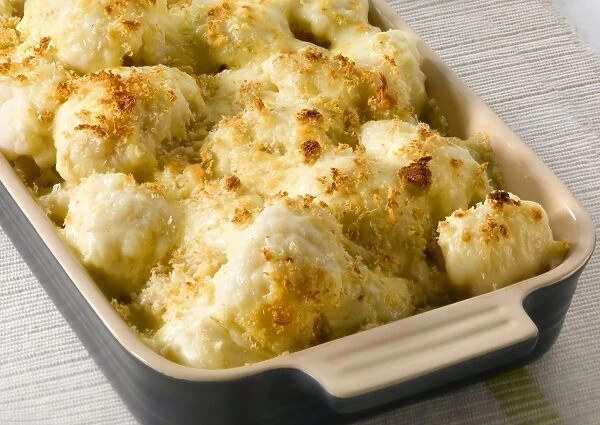 Freshly cooked cauliflower cheese in casserole dish on table